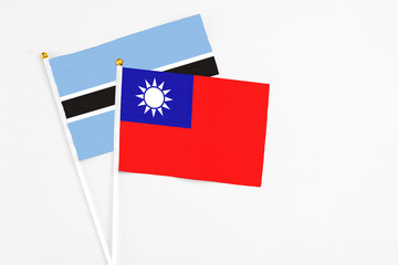 Taiwan and Botswana stick flags on white background. High quality fabric, miniature national flag. Peaceful global concept.White floor for copy space.