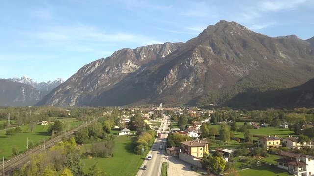 Aerial view of a small historic town Venzone in Northern Italy with red tiled roofs of old buildings and majestic Alps mountains.