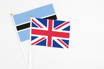 Fototapeta na wymiar United Kingdom and Botswana stick flags on white background. High quality fabric, miniature national flag. Peaceful global concept.White floor for copy space.