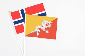 Bhutan and Bouvet Islands stick flags on white background. High quality fabric, miniature national flag. Peaceful global concept.White floor for copy space.