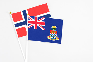 Fototapeta premium Cayman Islands and Bouvet Islands stick flags on white background. High quality fabric, miniature national flag. Peaceful global concept.White floor for copy space.