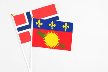 Guadeloupe and Bouvet Islands stick flags on white background. High quality fabric, miniature national flag. Peaceful global concept.White floor for copy space.