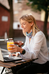 Young woman in cafe. Beautiful businesswoman drinking juice. Pretty student in cafe with lap top.