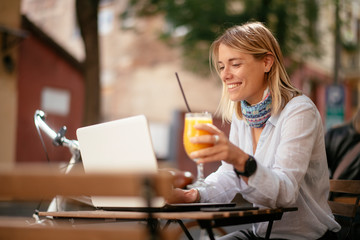 Young woman in cafe. Beautiful businesswoman drinking juice. Pretty student in cafe with lap top.