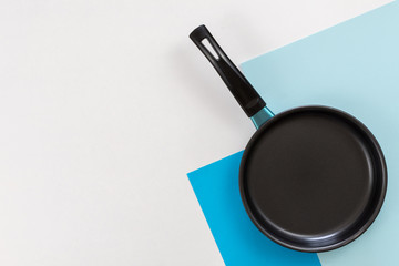 Frying pan on white and blue table.
