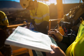 Construction miner workers signing working at height permit on open field job site prior to starting high risk work each shift construction mine site Australia - obrazy, fototapety, plakaty