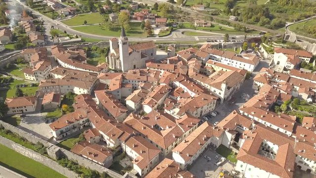 Top down aerial view of a small historic town Venzone in Northern Italy with red tiled roofs of old buildings.