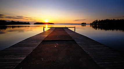 A large jetty leading out into a lake with sunset in the background