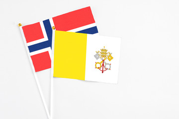 Vatican City and Bouvet Islands stick flags on white background. High quality fabric, miniature national flag. Peaceful global concept.White floor for copy space.