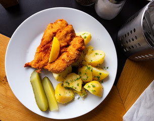 Top view of Parmesan breaded chicken with potatoes, pickles