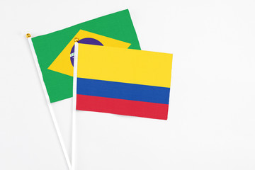 Colombia and Brazil stick flags on white background. High quality fabric, miniature national flag. Peaceful global concept.White floor for copy space.