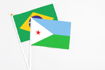 Djibouti and Brazil stick flags on white background. High quality fabric, miniature national flag. Peaceful global concept.White floor for copy space.