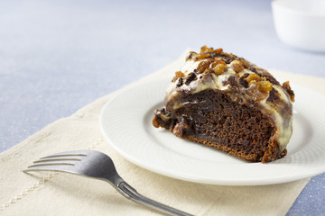 Delicious chocolate cake with raisins and cream. Piece of Chocolate Cake on a Plate. Sweet food. Sweet dessert. Light bakcground. Close up.