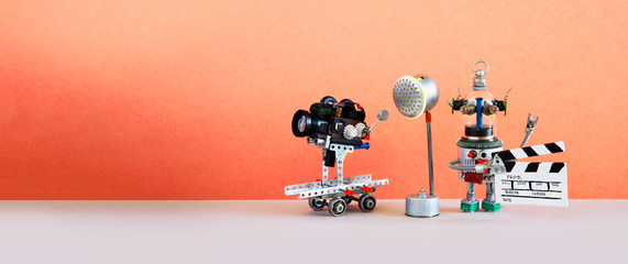 Comical art television industry equipment. Backstage studio with camera camcorder on wheels, projector spotlight. Funny mechanical robot toy with clapperboard. Pink background. copy space