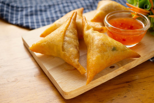 Samosas on wooden board.
