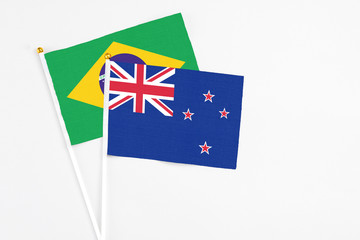Fototapeta premium New Zealand and Brazil stick flags on white background. High quality fabric, miniature national flag. Peaceful global concept.White floor for copy space.