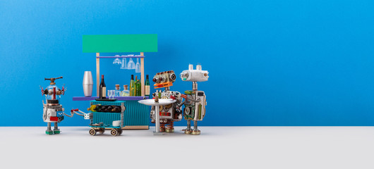 Funny toy sommelier carries a waiter's trolley. Two guest robots are waiting for an order with drinks. Bar counter on blue background. copy space