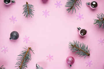 Christmas composition. Christmas decorations pink balls and snowflakes with Christmas tree branches on a pink background. Flat lay, top view, place for text.