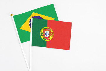 Portugal and Brazil stick flags on white background. High quality fabric, miniature national flag. Peaceful global concept.White floor for copy space.