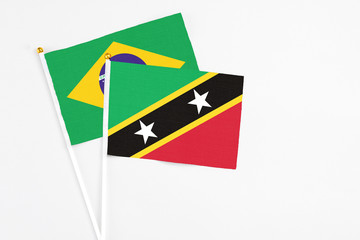 Saint Kitts And Nevis and Brazil stick flags on white background. High quality fabric, miniature national flag. Peaceful global concept.White floor for copy space.