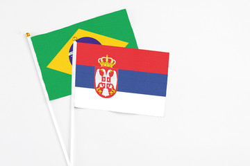 Serbia and Brazil stick flags on white background. High quality fabric, miniature national flag. Peaceful global concept.White floor for copy space.