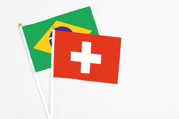 Obraz premium Switzerland and Brazil stick flags on white background. High quality fabric, miniature national flag. Peaceful global concept.White floor for copy space.