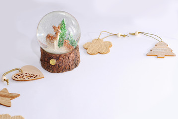 Christmas glass ball with snow with two deers inside with fir tree  and beautiful wooden decor toys Natural style minimalistic design on the white background New years winter holidays gift card
