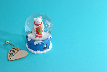 Christmas glass ball with snow with bear wearing red scarf hugs kid inside toys and wooden heart symbol Natural style minimalistic design on the light b background New years winter holidays gift card