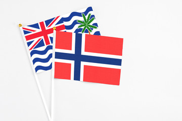 Bouvet Islands and British Indian Ocean Territory stick flags on white background. High quality fabric, miniature national flag. Peaceful global concept.White floor for copy space.