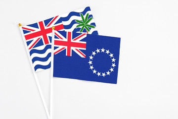 Fototapeta premium Cook Islands and British Indian Ocean Territory stick flags on white background. High quality fabric, miniature national flag. Peaceful global concept.White floor for copy space.