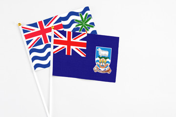 Fototapeta premium Falkland Islands and British Indian Ocean Territory stick flags on white background. High quality fabric, miniature national flag. Peaceful global concept.White floor for copy space.
