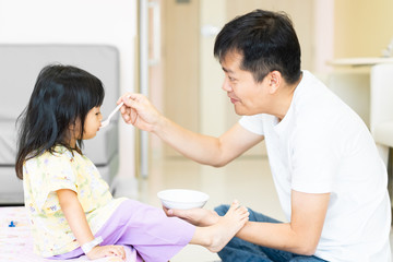Asian father is feeding breakfast to his daughter in the hospital room, the sick asian little girl admit as a patient with her illness and need parent supporting, concept of healthcare in hospital.