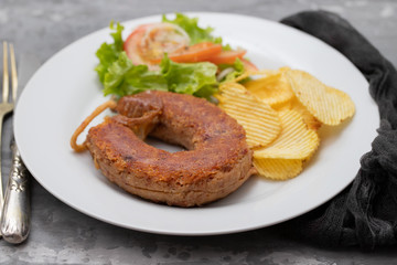 typical portuguese smoked sausage alheira with fried potato and salad on white dish