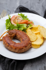 typical portuguese smoked sausage alheira with fried potato and salad on white dish