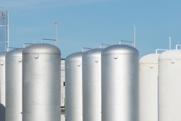 Large aluminum containers for storing near nuclear power plant. Metal elevator. Modern aluminum or steel storage tanks or barrels against the blue sky