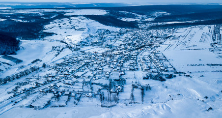 Fototapeta na wymiar aerial view village among the fields and forests in winter. winter landscape snow covered field and trees in countryside.