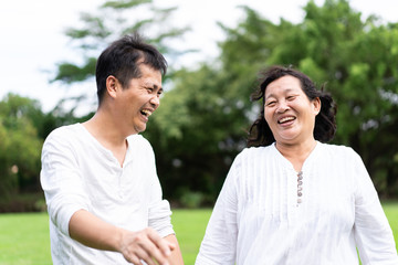 Asian mother and young son are walking and talking together in the park with fully happiness moment, concept of adult son take care elderly mother in family lifestyle.