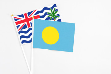 Palau and British Indian Ocean Territory stick flags on white background. High quality fabric, miniature national flag. Peaceful global concept.White floor for copy space.