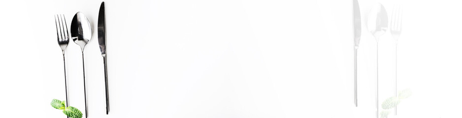 Simple laconic design cutlery set on white table with mild dark. Copy space. Top view. Wide white half banner background. Faded foggy.