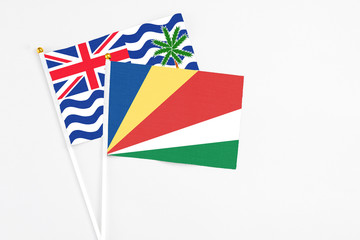 Seychelles and British Indian Ocean Territory stick flags on white background. High quality fabric, miniature national flag. Peaceful global concept.White floor for copy space.
