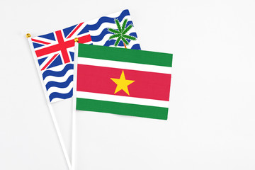 Suriname and British Indian Ocean Territory stick flags on white background. High quality fabric, miniature national flag. Peaceful global concept.White floor for copy space.