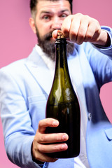 Celebration, drink, alcohol and holidays concept. Bearded man opens bottle. Sommelier with wine...
