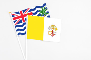 Vatican City and British Indian Ocean Territory stick flags on white background. High quality fabric, miniature national flag. Peaceful global concept.White floor for copy space.