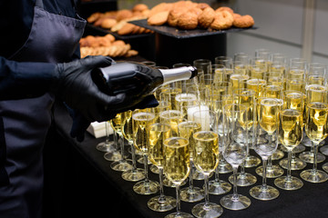 Waiter pours champagne into the glasses