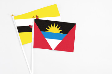 Antigua and Barbuda and Brunei stick flags on white background. High quality fabric, miniature national flag. Peaceful global concept.White floor for copy space.