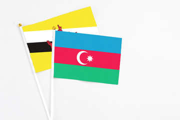 Azerbaijan and Brunei stick flags on white background. High quality fabric, miniature national flag. Peaceful global concept.White floor for copy space.