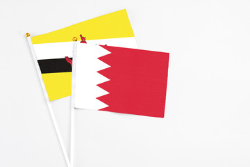 Bahrain and Brunei stick flags on white background. High quality fabric, miniature national flag. Peaceful global concept.White floor for copy space.