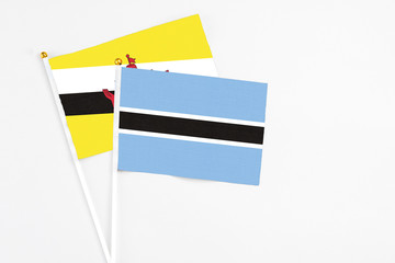 Botswana and Brunei stick flags on white background. High quality fabric, miniature national flag. Peaceful global concept.White floor for copy space.