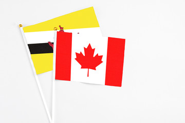 Canada and Brunei stick flags on white background. High quality fabric, miniature national flag. Peaceful global concept.White floor for copy space.