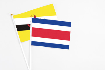 Costa Rica and Brunei stick flags on white background. High quality fabric, miniature national flag. Peaceful global concept.White floor for copy space.
